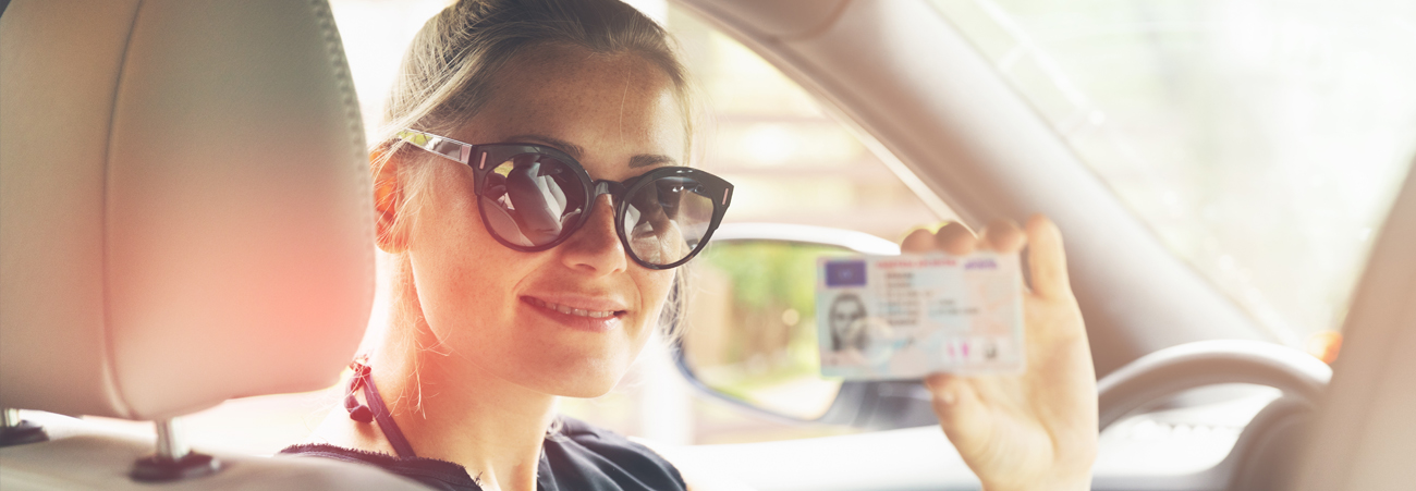 Frau im Auto zeigt Führerschein