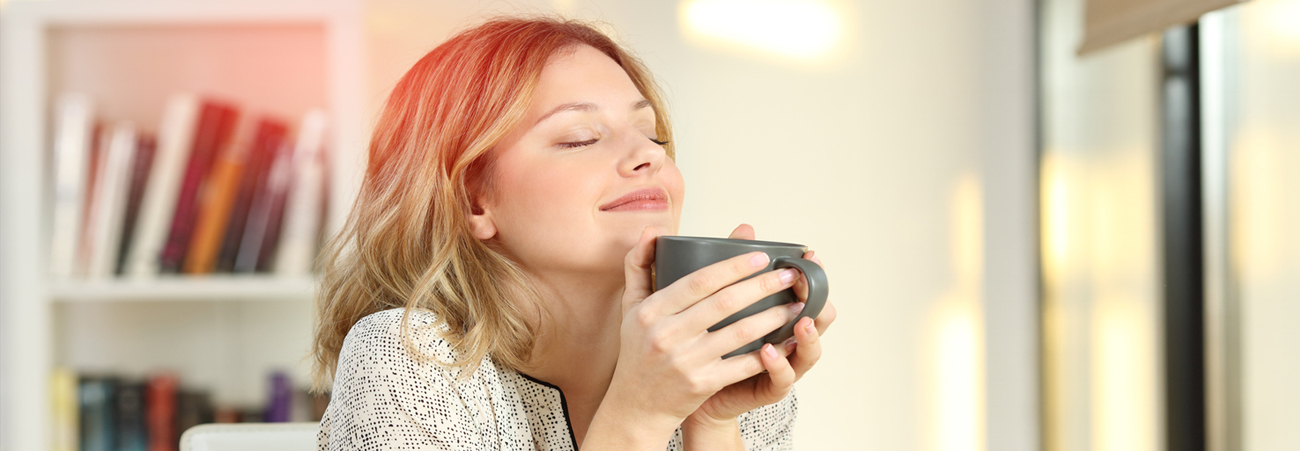 Junge Frau mit Teetasse lächelt versonnen
