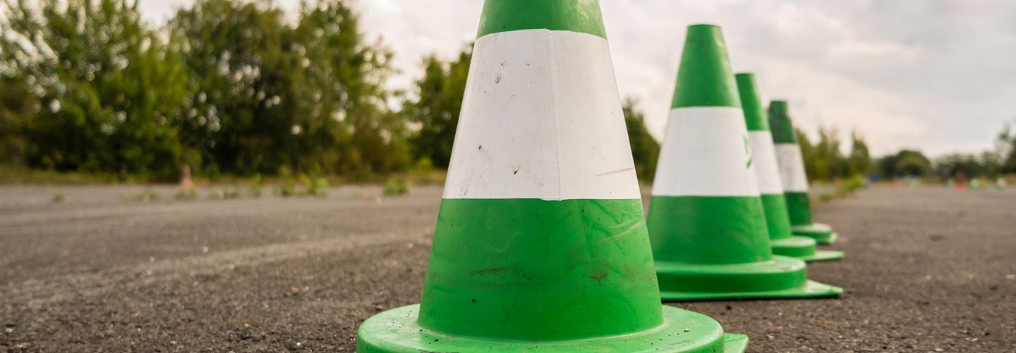 Grüne Verkehrshütchen auf einer Fahrbahn als Symbol für Fahrsicherheitstraining und sicheres Autofahren.