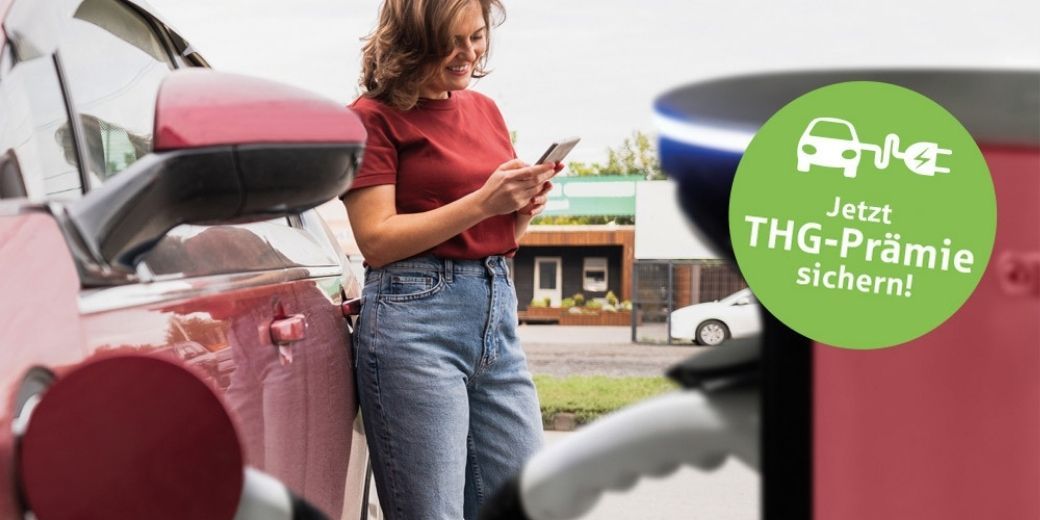 Frau lädt ein rotes Elektroauto an einer Ladesäule als Symbol für E-Mobilität und THG-Prämie.