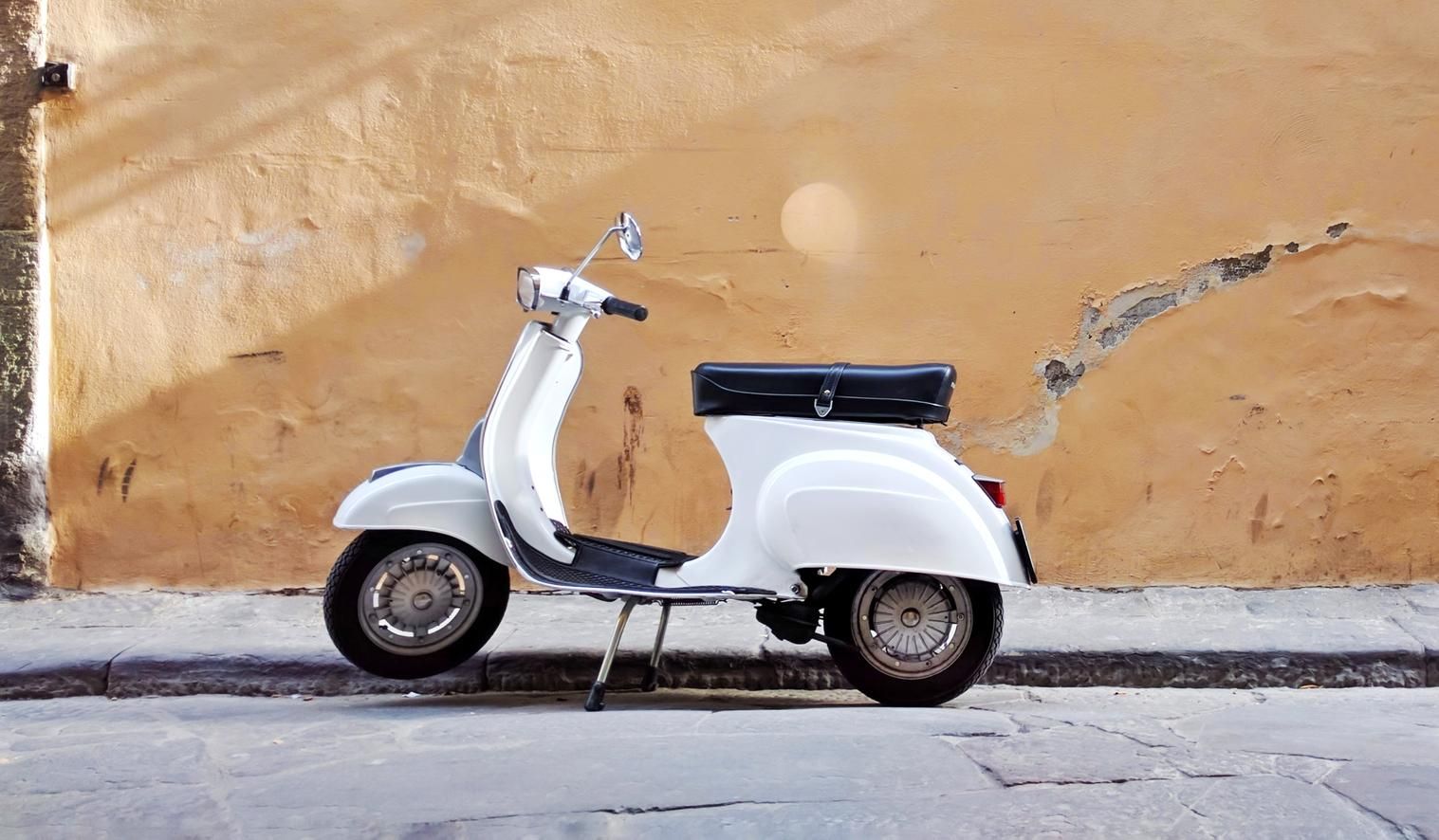 Eine weiße Vespa steht vor einer Hauswand