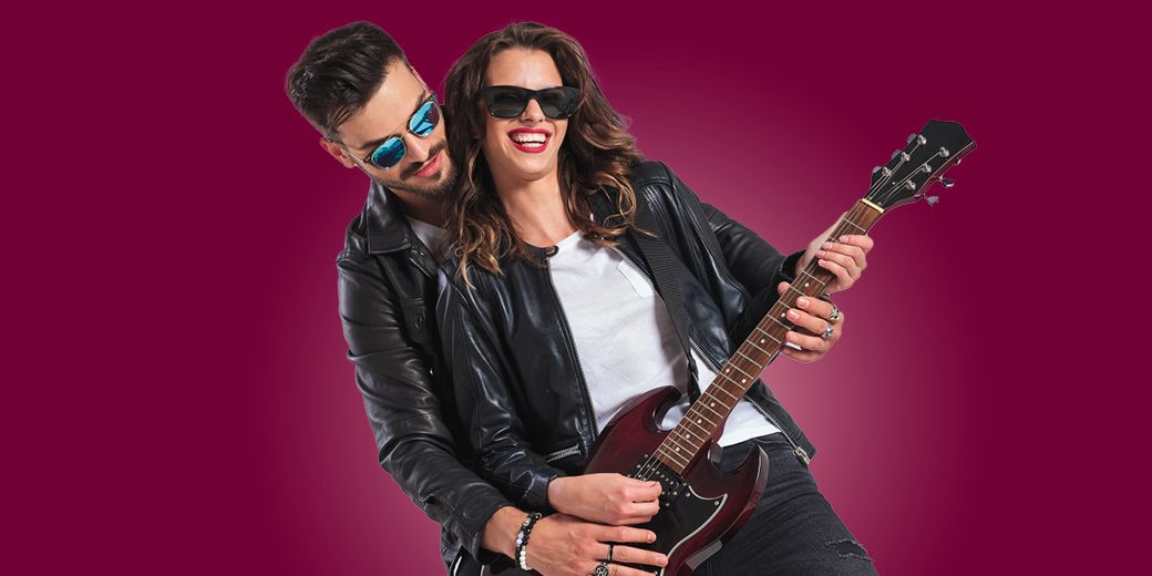Junges Paar mit Sonnenbrillen und E-Gitarre vor lila Hintergrund als Symbol für junge Leute, Freizeit und individuelle Absicherung.