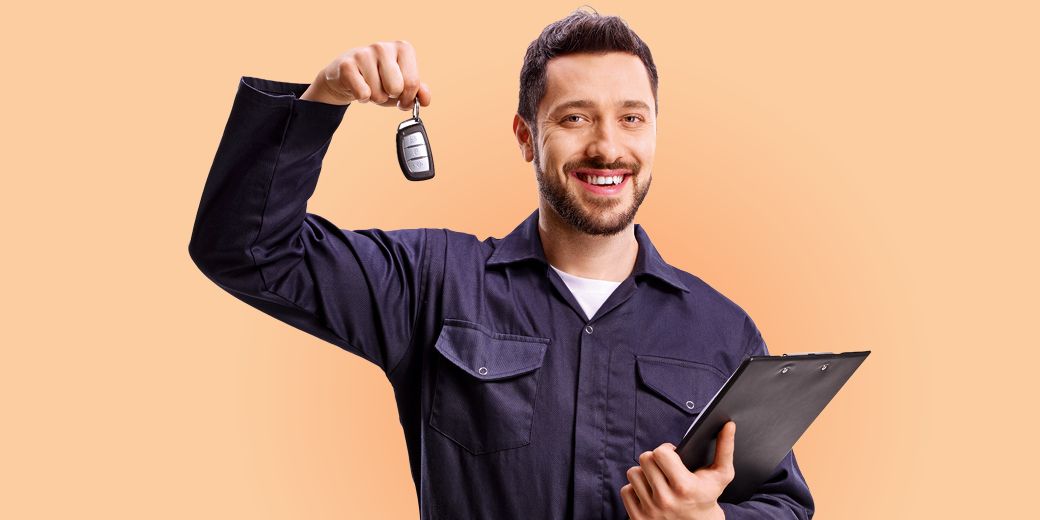 Mitarbeiter einer Werkstatt hält Autoschlüssel und Klemmbrett als Symbol für Werkstatt-Management und schnelle Hilfe im Kasko-Schadenfall.
