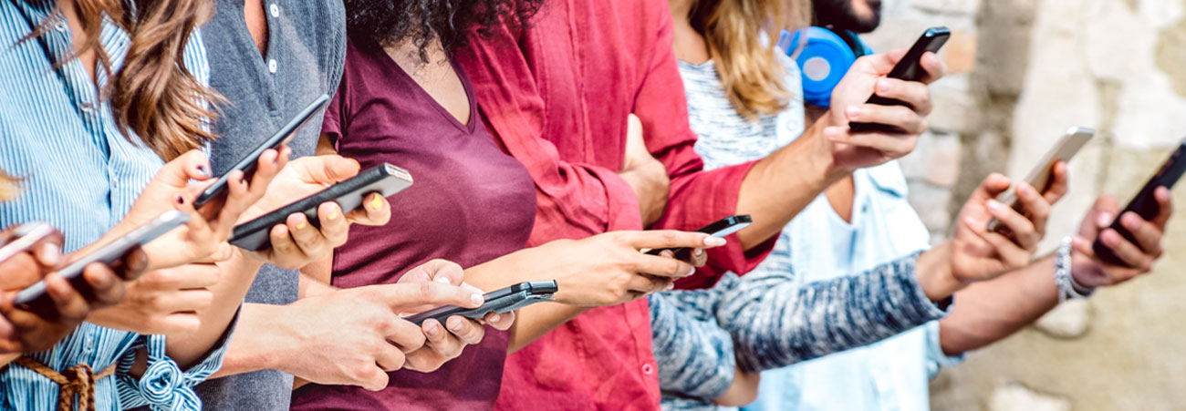 Gruppe von Menschen die nebeneinander stehen und auf ihr Smartphone schauen