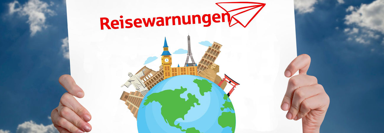 Hände halten ein Schild mit "Reisewarnungen" hoch