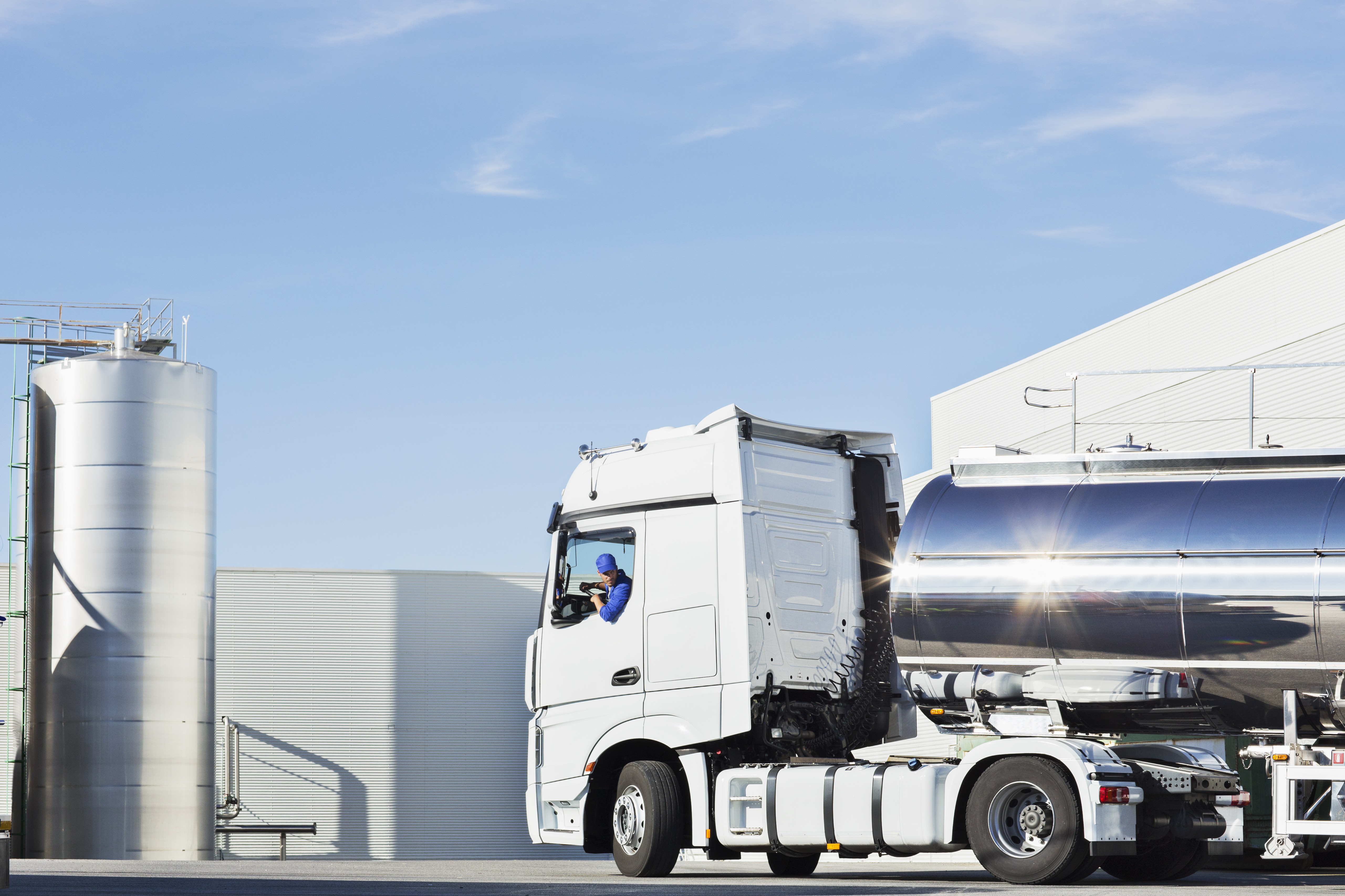 Tanklastwagen steht vor industriellen Lagertanks auf einem Betriebsgelände