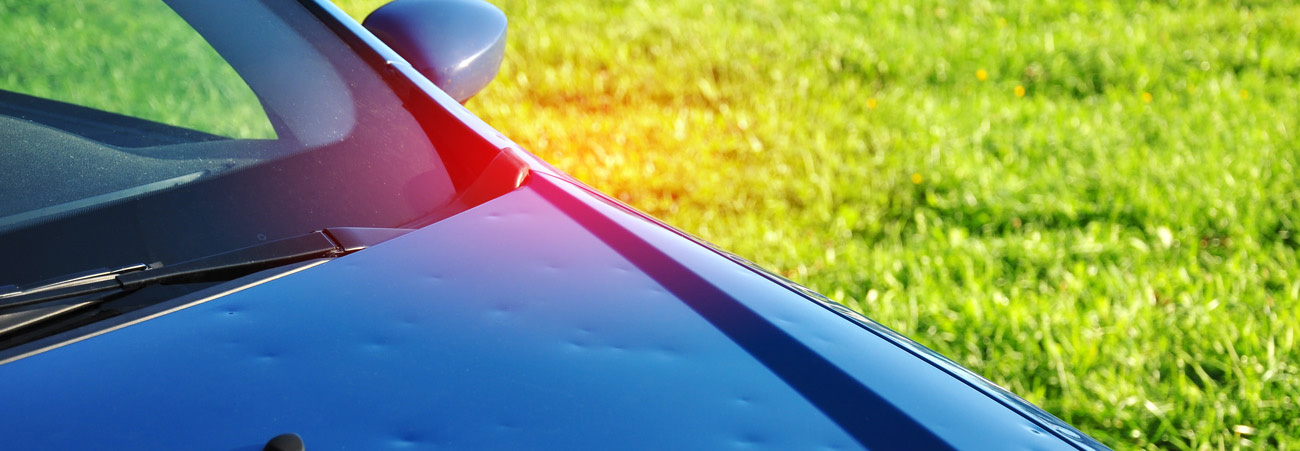 ein blaues Auto hat Dellen von Hagelkörnern auf der Motorhaube
