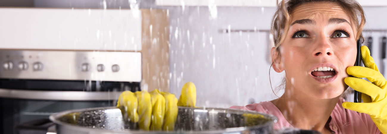 Frau fängt Wasser auf, das von der Decke tropft