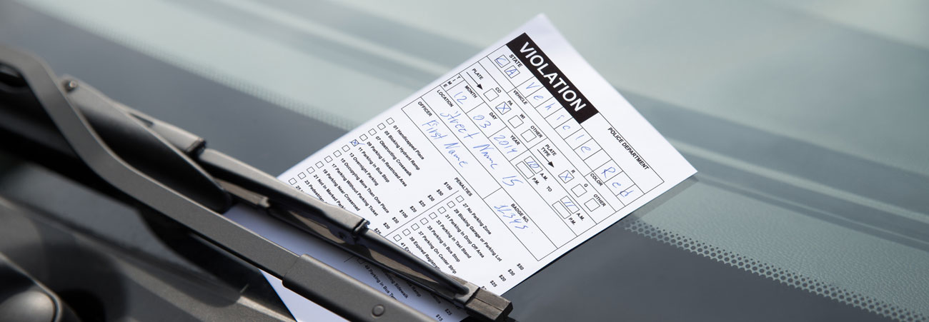 Knöllchen/Strafzettel klemmt unter Scheibenwischer eines Autos