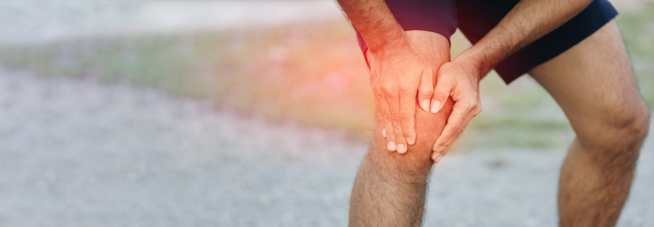 Sportler greift sich schmerzendes Knie beim Joggen
