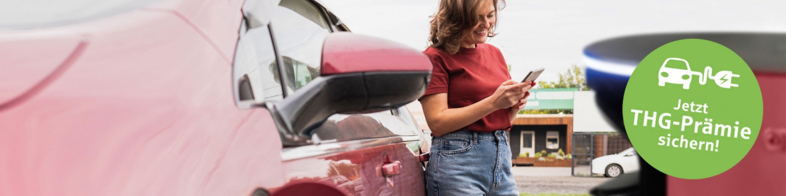 Frau lädt ein rotes Elektroauto an einer Ladesäule als Symbol für E-Mobilität und THG-Prämie.