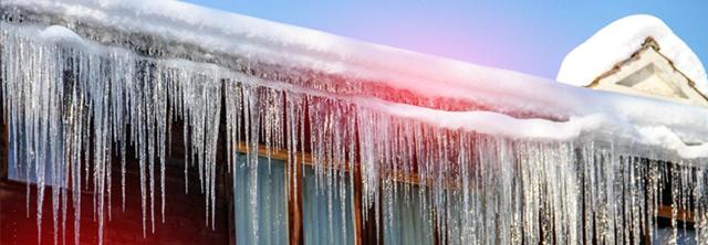 Viele Eiszapfen hängen vom Dach eines Hauses