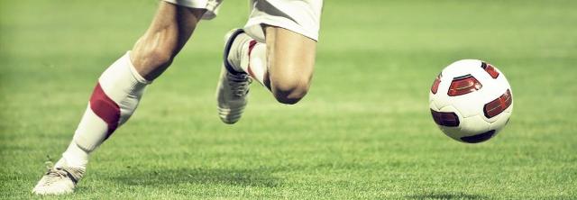 Fußballerbeine im Lauf hinter einem Ball her