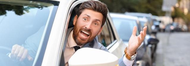 Genervter Autofahrer schaut schimpfend aus dem Autofenster