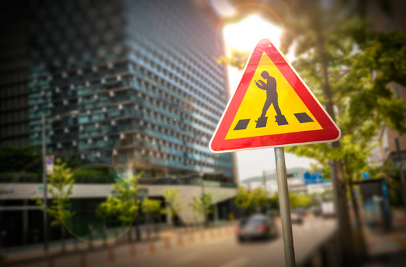 Verkehrsschild Achtung mit mit Handy läuft über Straße