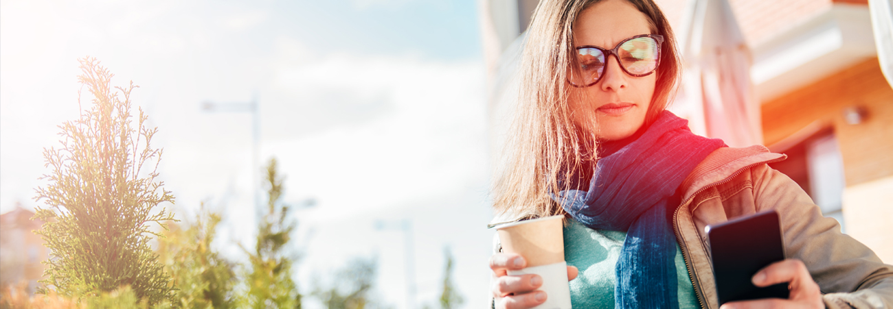 Frau mit Kaffee und Smartphone in der Hand