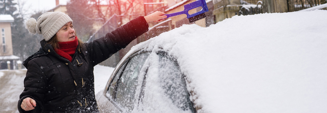 Frau befreit Auto von Schnee