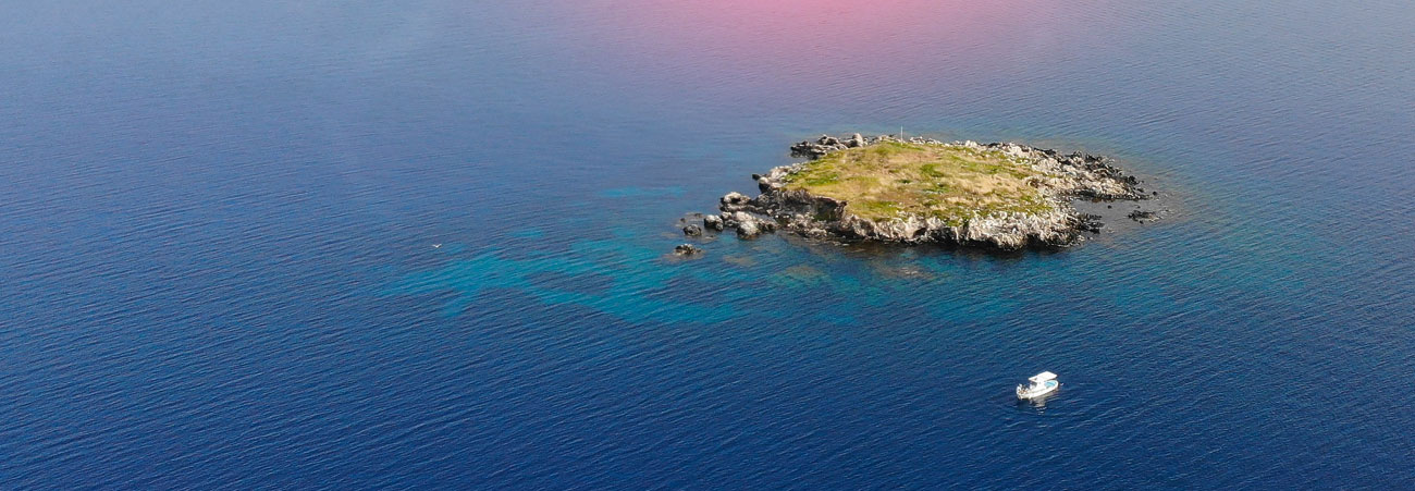 Winziges, einsames Eiland im Meer. Ein coronafreier Urlaubsort, auf den ein Boot zu steuert. 