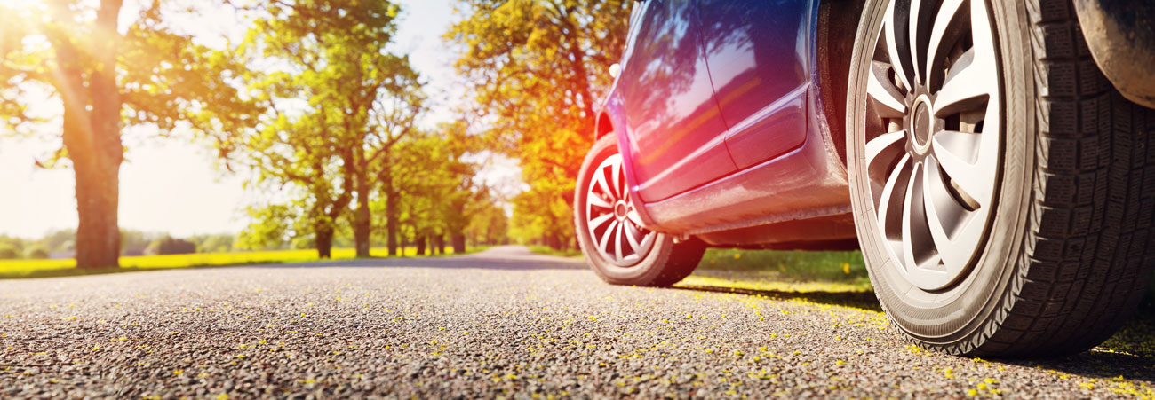 Auto fährt auf Landstraße im Spätsommer. Die Typklasse des Fahrzeuges entscheidet mit, wieviel seine Kfz-Versicherung kostet.