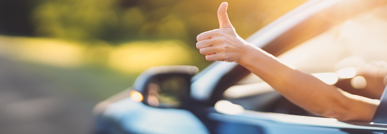 Fahrer hält Hand mit Daumen nach oben aus dem Autofenster