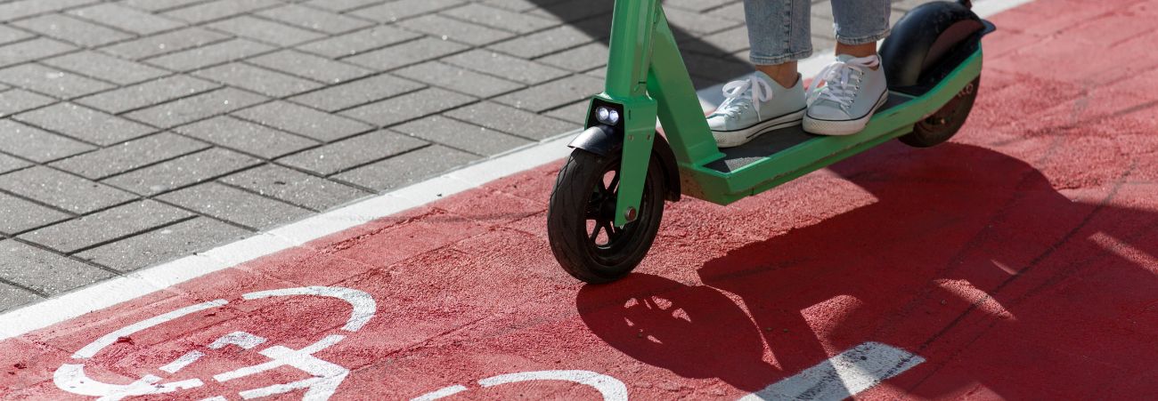 Zwei Füße auf E-Scooter fahren auf rotem Fahrradweg