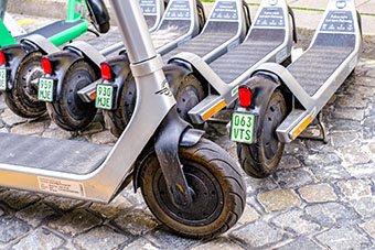 Nahaufnahme: abgestellte Sharing-E-Scooter mit sichtbaren Hinterrädern und Kennzeichen