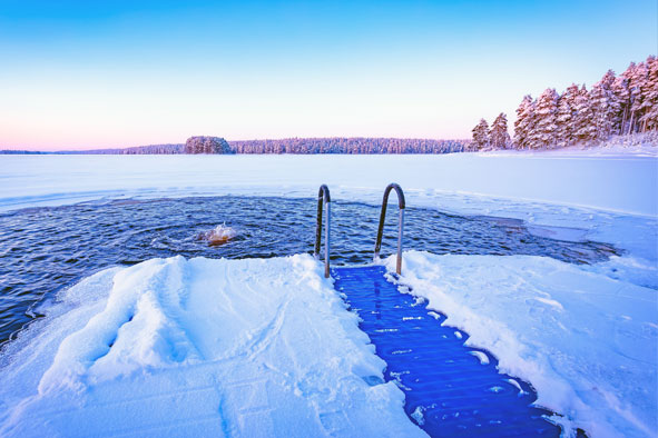  Verschneiter Steg mit Leiter zu einem eisigen See für Winterbaden bei Sonnenaufgang