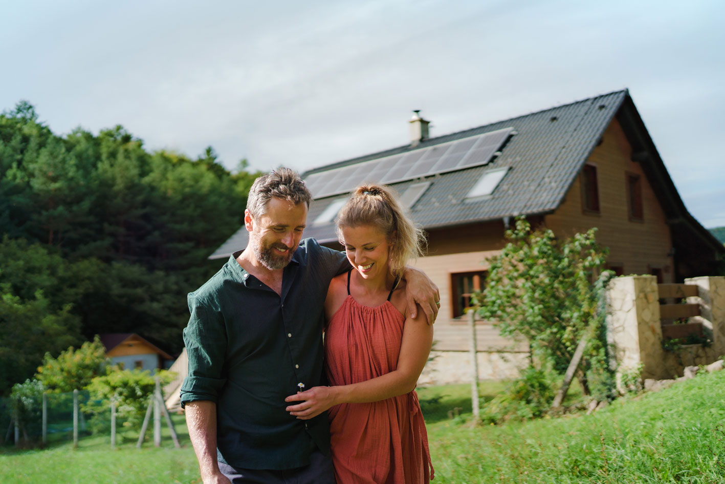 Paar steht vor Eigenheim mit Photovoltaikanlage