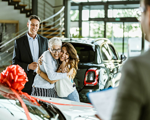 Oma und Enkelin umarmen sich im Autohaus