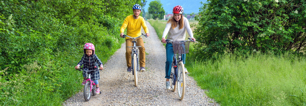 Junge Familie unternimmt eine Radtour im Grünen.