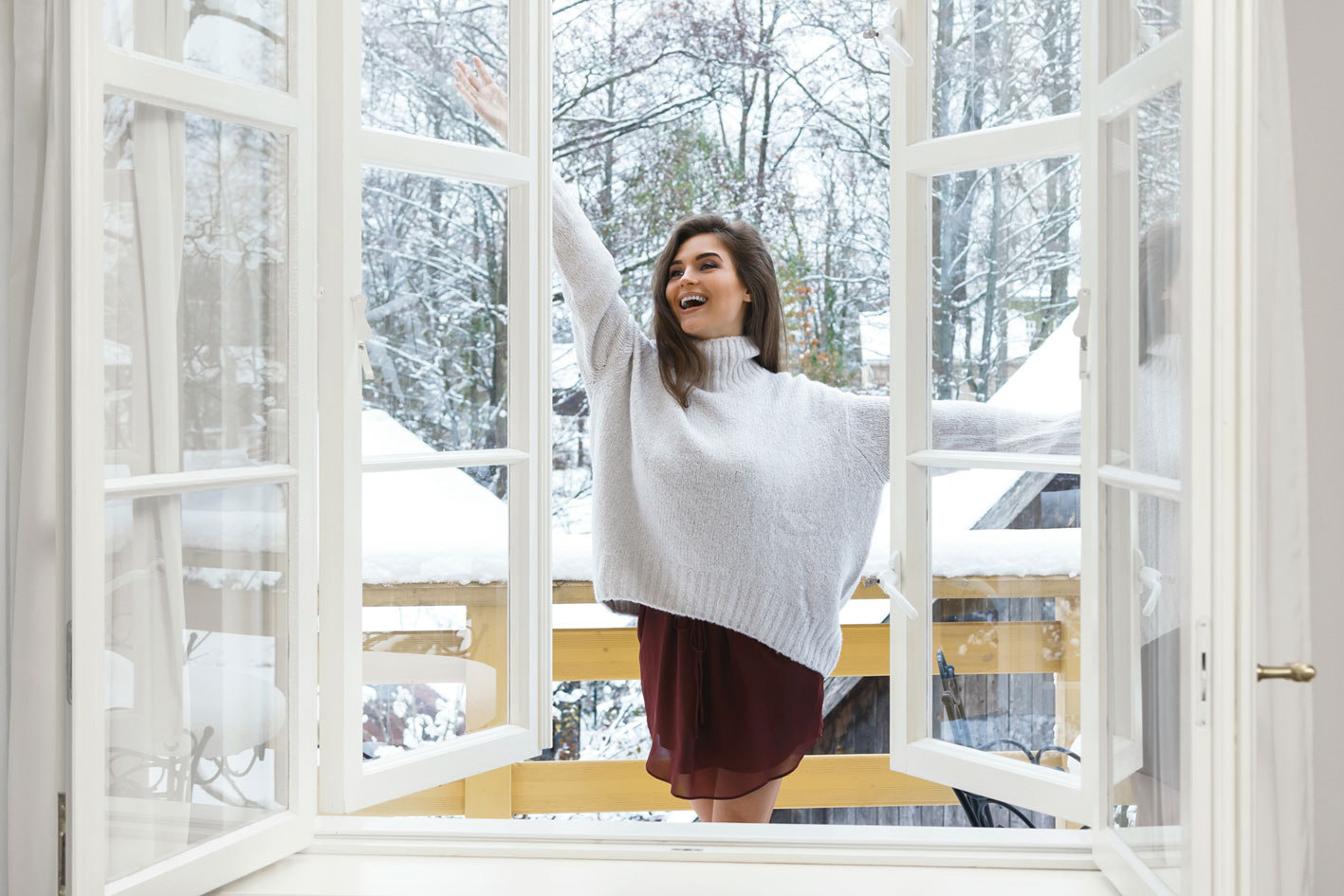 Junge Frau öffnet Fenster weit.