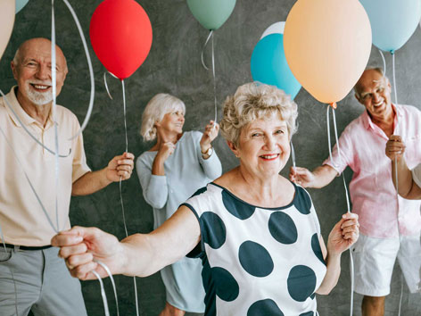 ältere Menschen halten lächelnd Luftballons