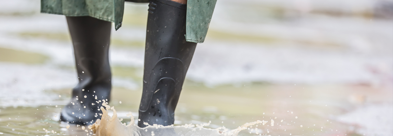 Mann steht mit Gummistiefeln im Wasser