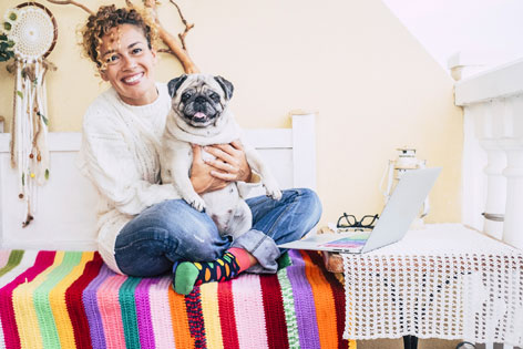 Frau mit Hund auf buntem Sofa