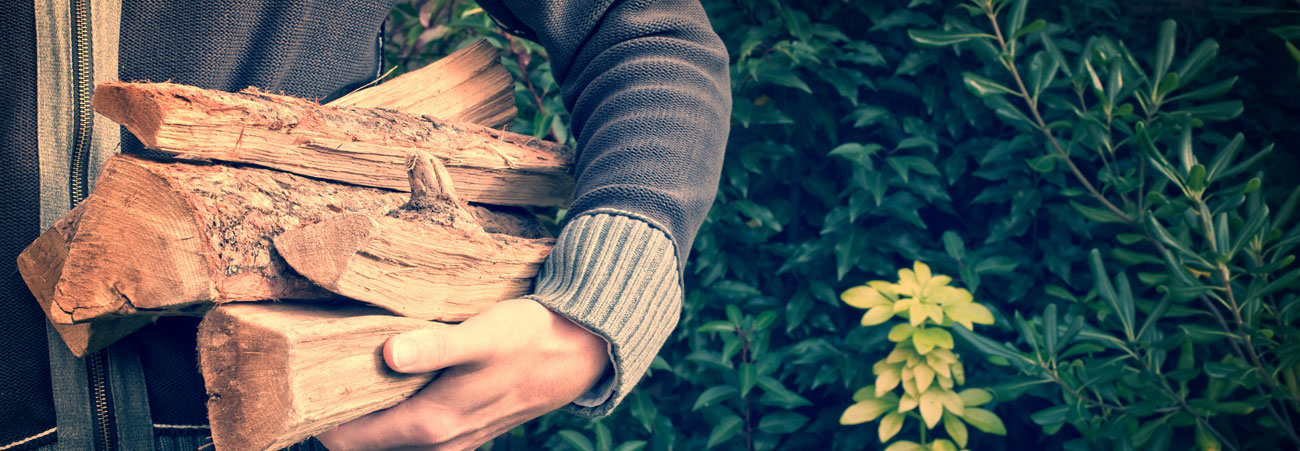 Ein Mann trägt Holzscheite im Arm.