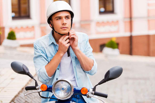 Junger Mann mit Helm auf Roller.