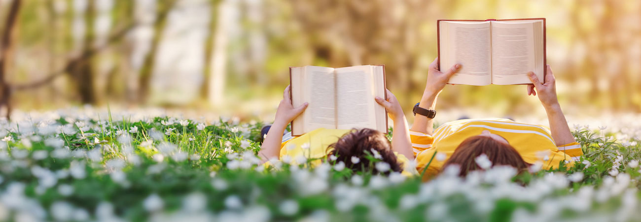 Mutter und Sohn lesen Buch auf einer Wiese