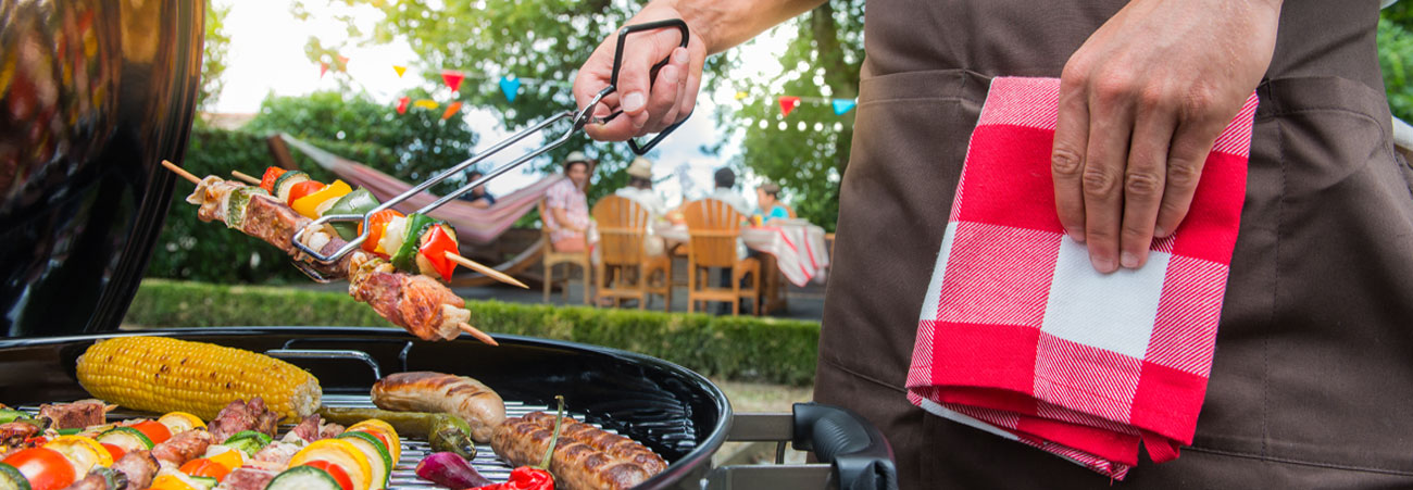 Mann legt Fleischspieße auf den Grill