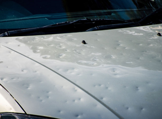 massiver Hagelschaden, Motorhaube von Auto mit vielen Dellen