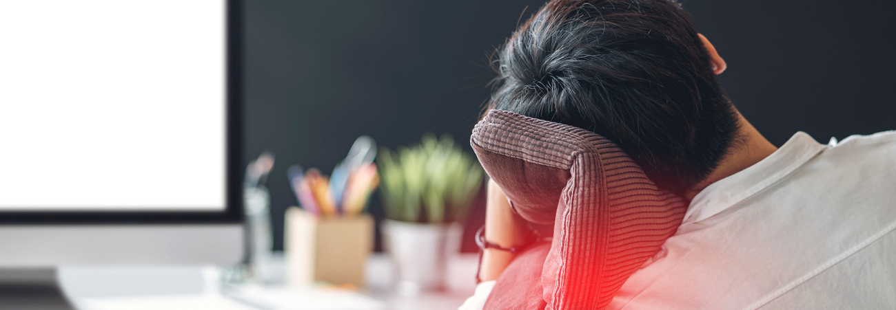 Junger Mann sitzt müde am Schreibtisch vor dem Computer.