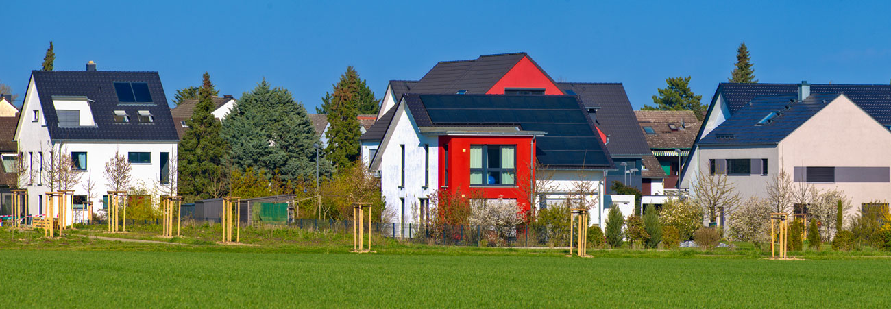 Siedlung aus modernen Einfamilienhäusern am Rand einer grünen Wiese