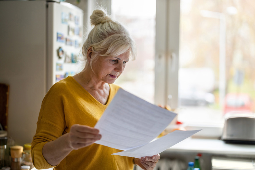 Aeltere Frau liest ein Schriftstück