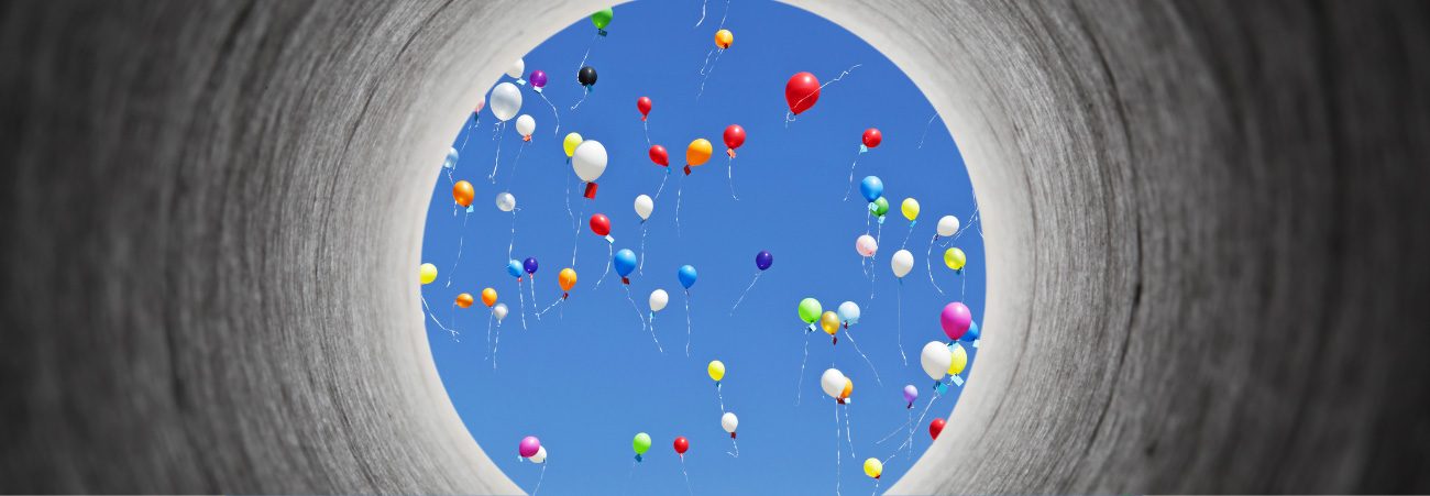 Am Ende eines Tunnels sind blauer Himmel und bunte Luftballons zu sehen