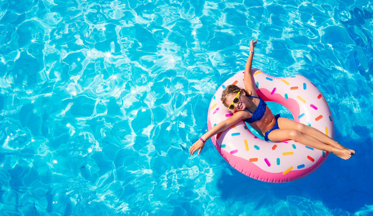 Maedchen sitzt im Schwimmring im Pool