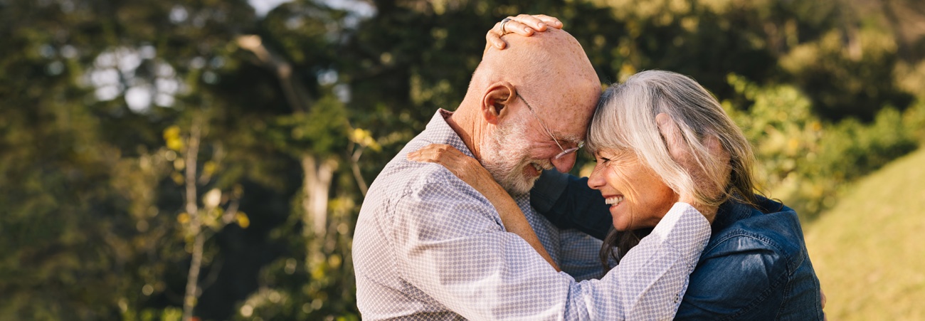 Rentnerpaar umarmt sich lächelnd