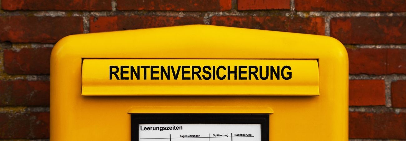 Gelber Briefkasten an roter Ziegelmauer mit Schriftzug Rentenversicherung auf der Einwurfklappe