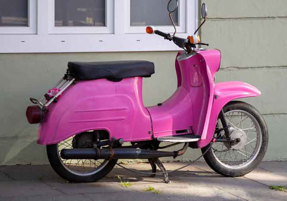 Rosa Moped steht vor einem Haus.