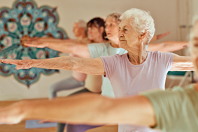 Seniorin streckt beim Yoga Arm aus