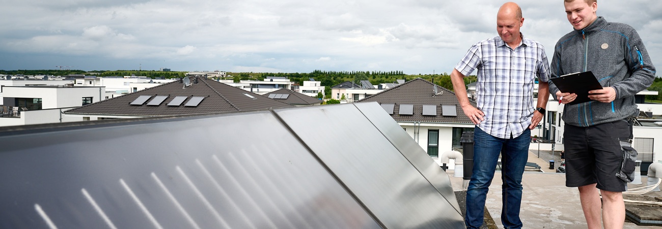 Zwei Männer begutachten eine Photovoltaikanlage auf dem Dach.