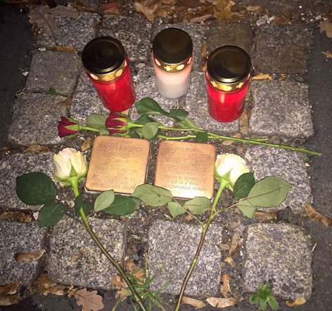 Stolpersteine mit Blumen und Lichtern geschmückt